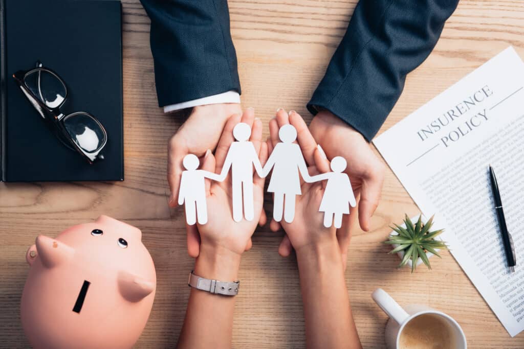 top view of lawyer and woman holding paper cut family near cup of coffee, insurance policy