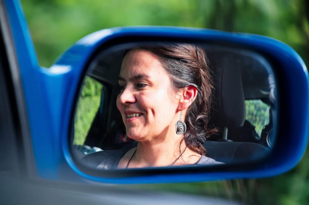 Reflection of mature beautiful woman in side rearview mirror