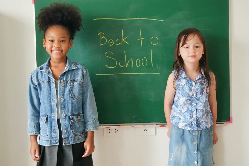 Happy little Girls against Chalkboard With Back To School