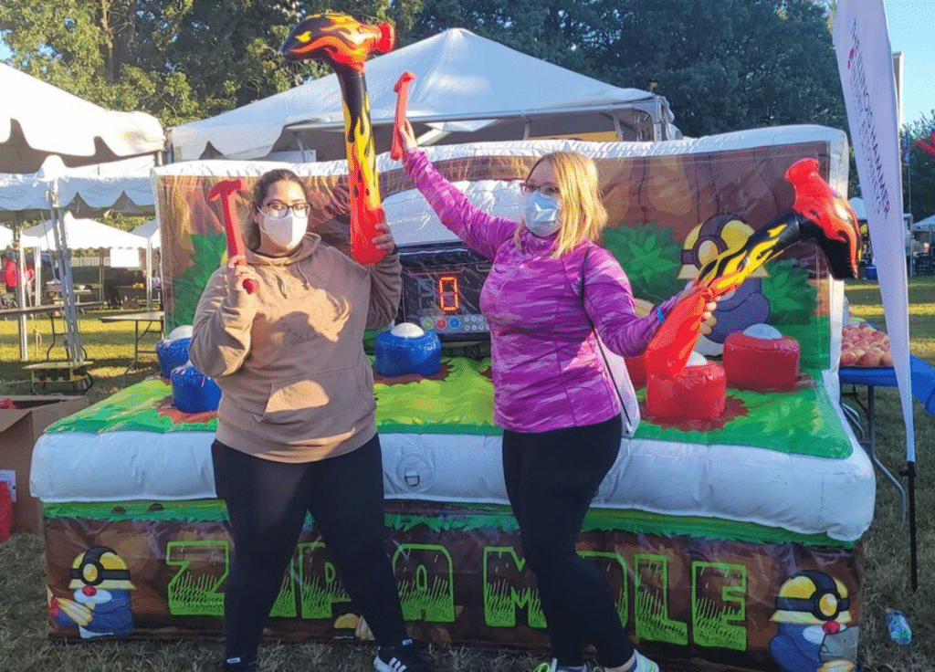 Two members of the Illinois Hammer team at Race Judicata in Lincoln Park in front of attraction (like whack a mole but called zap a mole) with inflatable hammers ready to play!