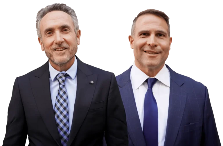 Portrait of Bradley and Dominic Maciariello, professional lawyers, standing side by side in suits and ties, smiling at the camera.