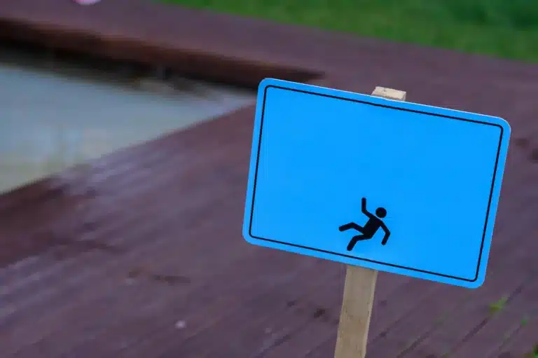 caution wet floor warning sign near swimming pool in hotel.