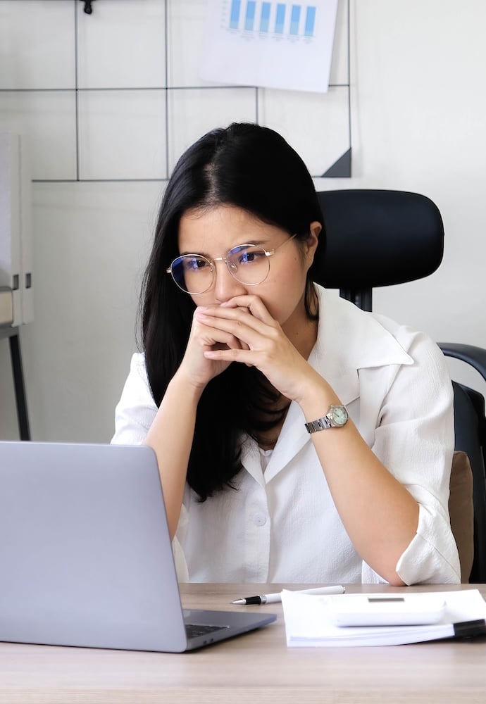 Tired female employee holding head on hand, looking at computer screen, doing hard task, having problem with computer software. Stressed exhausted businesswoman suffering from headache, feeling bored.